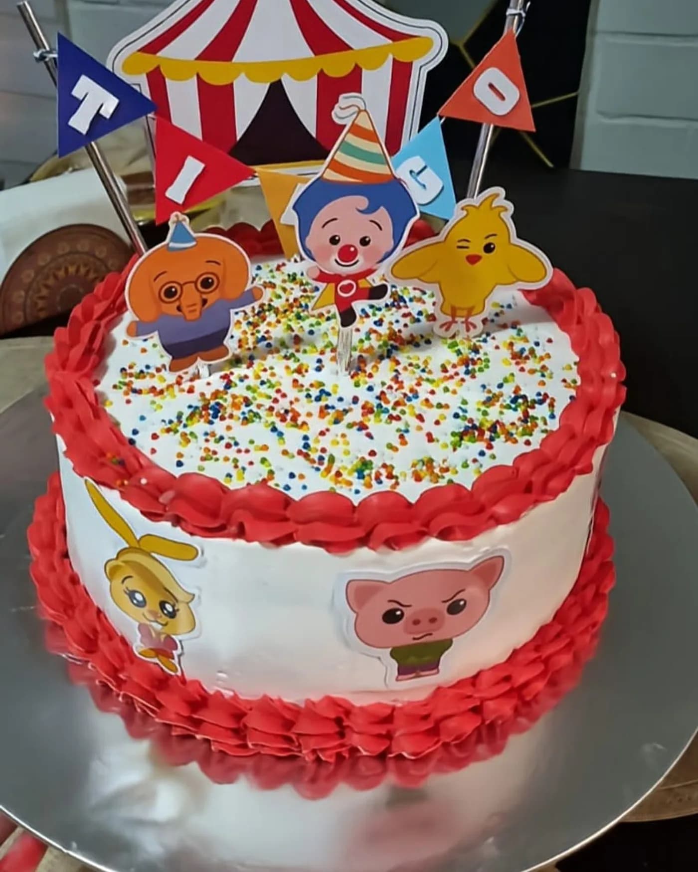 Torta clásica con grageas de colores, banderines y toppers de personajes